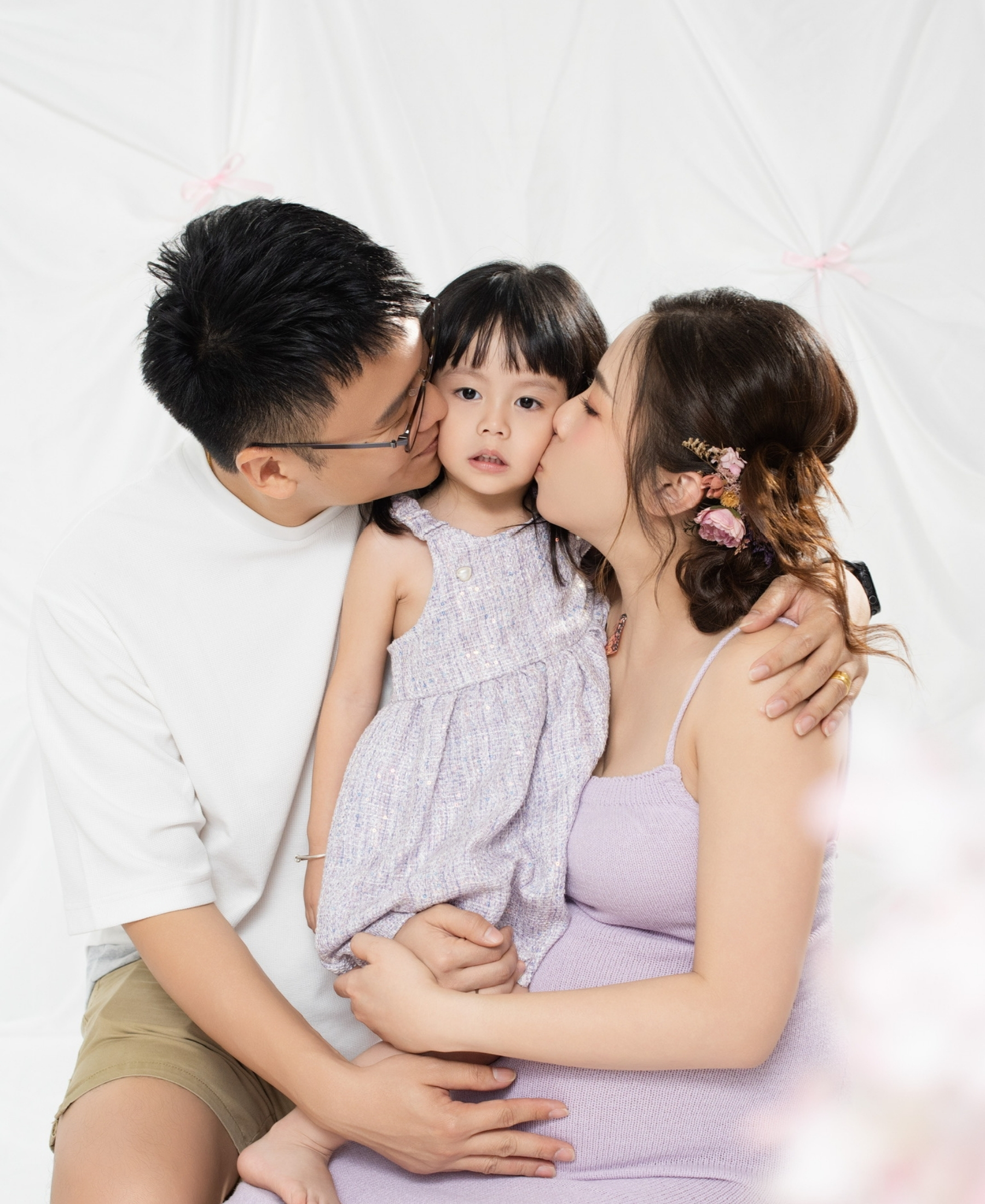 Father and mother kissing their daughter